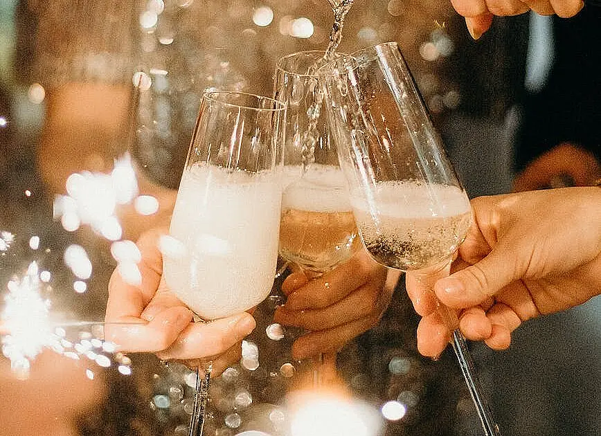 person pouring champagne on champagne flutes